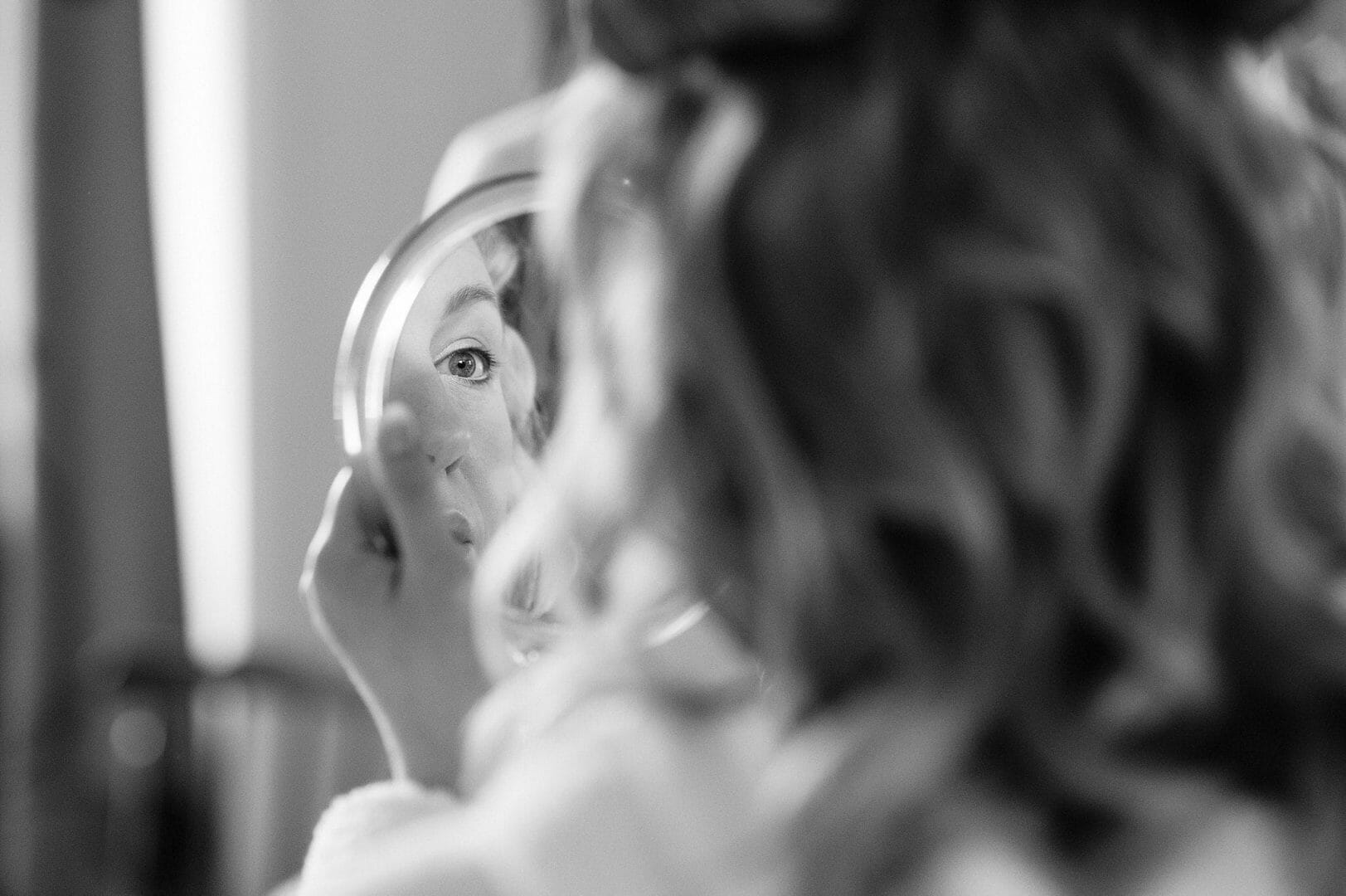 Bride checks her makeup in the mirror at the King John Inn