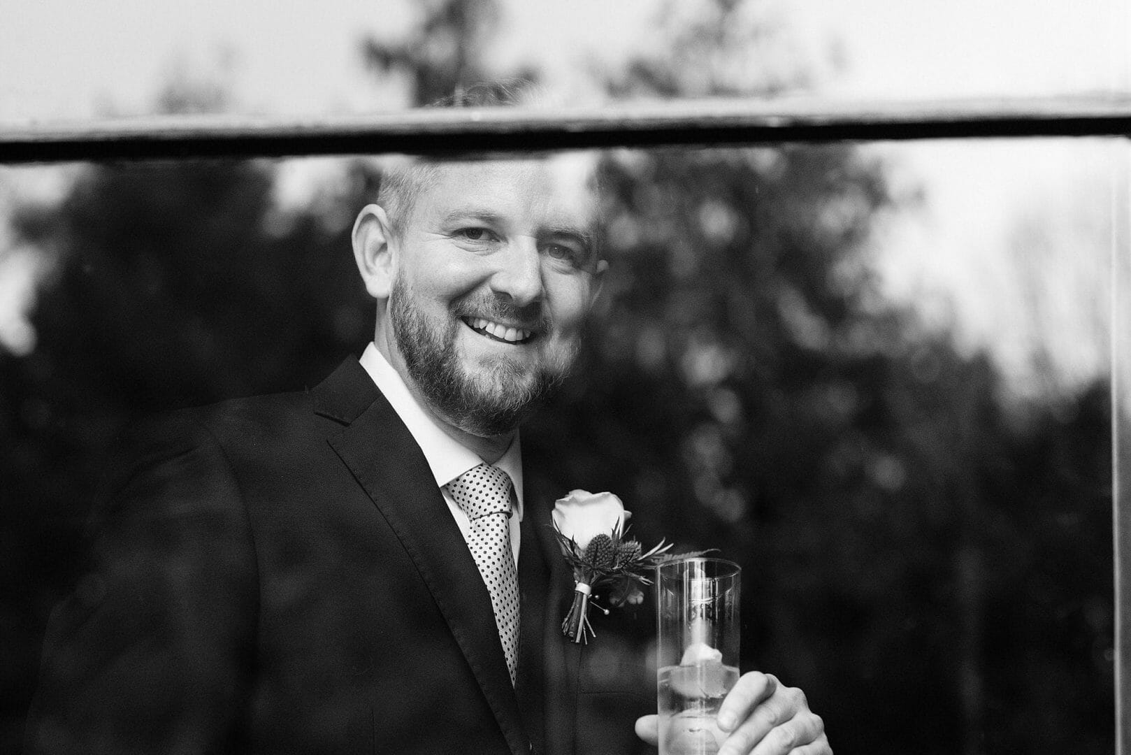 Groom stands by the window at the Larmertree Gardens - Wiltshire wedding