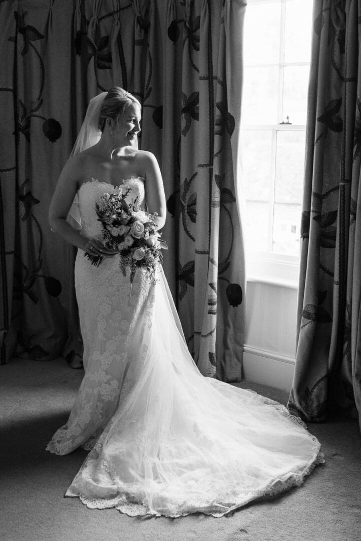 Bride stands by the window at the King John inn - Wiltshire wedding