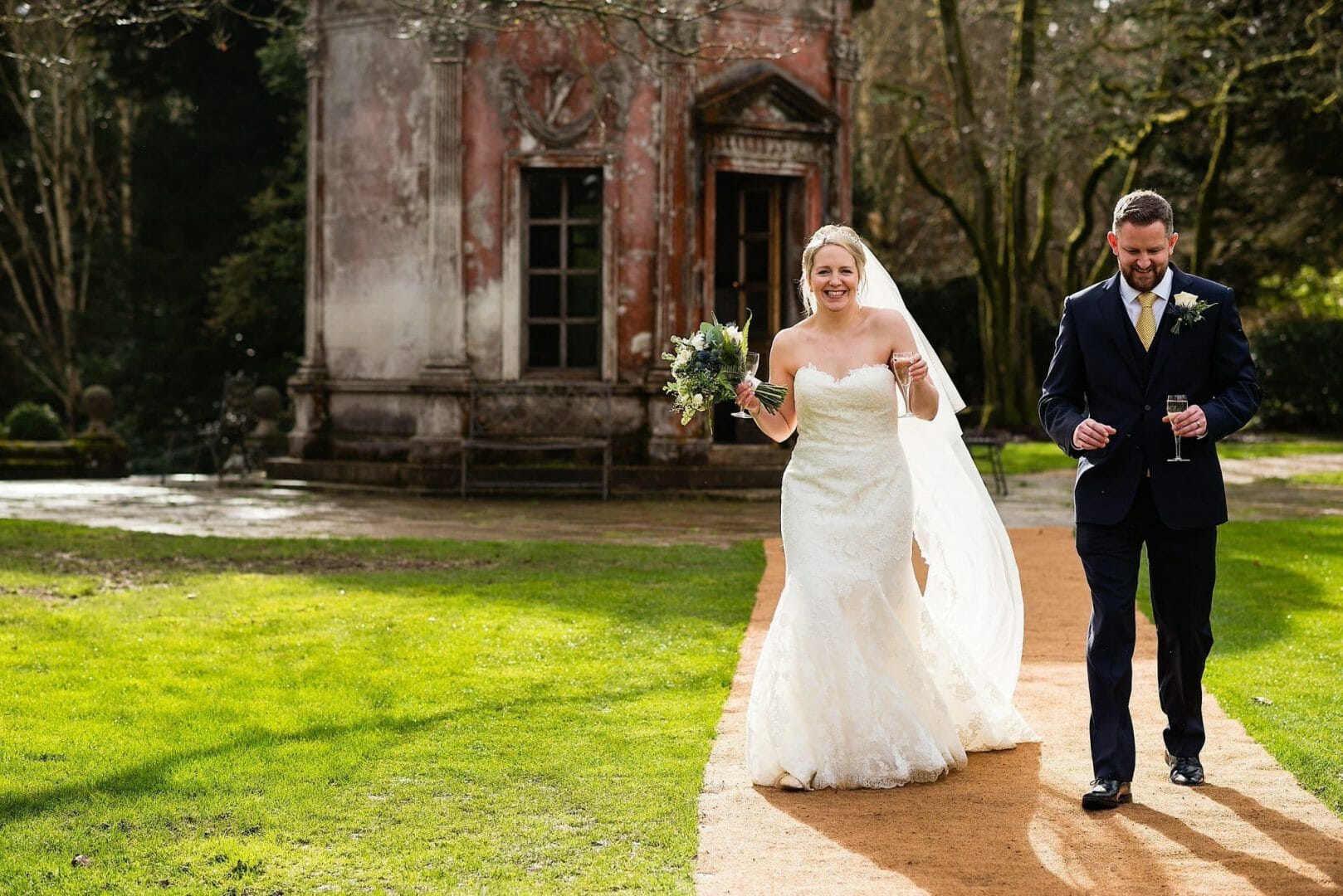 Larmertree garden wedding 64 Happy bride walks with husband at Larmer Tree Gardens