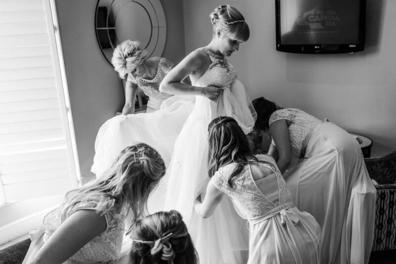 Bride being dressed by bridal party