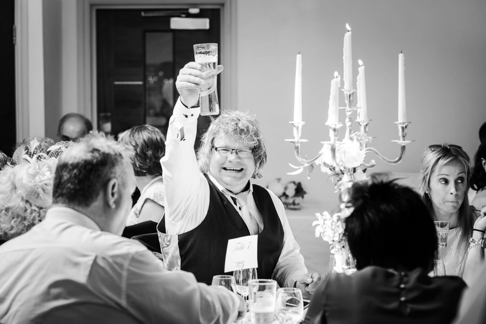 Happy wedding guest salutes with beer