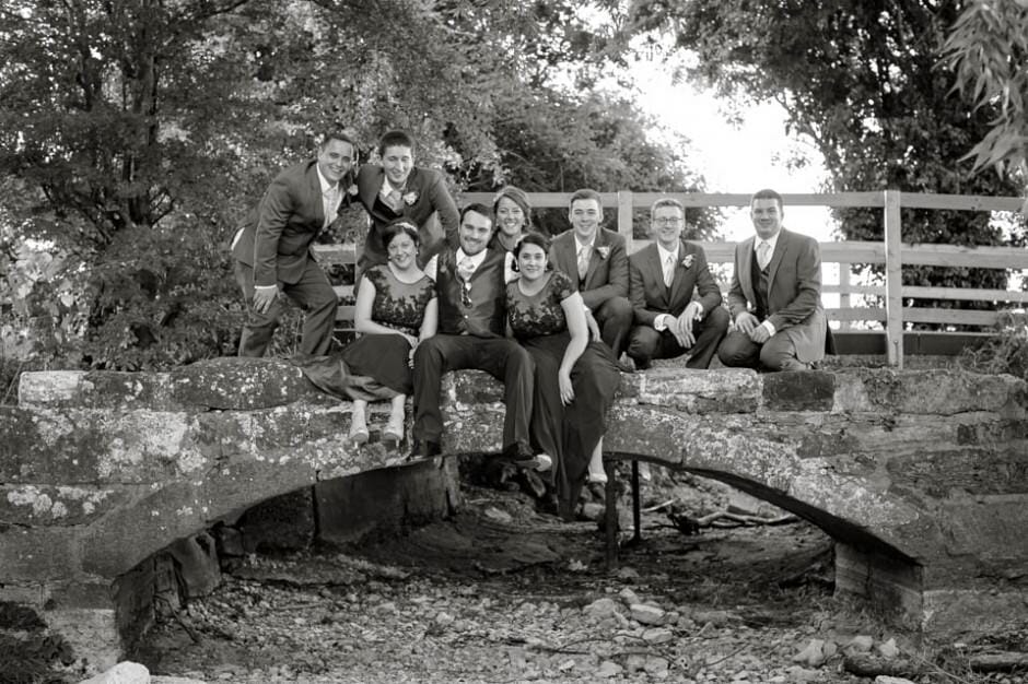 Gromsmen and Bridesmaids hanging out on a stone bridge