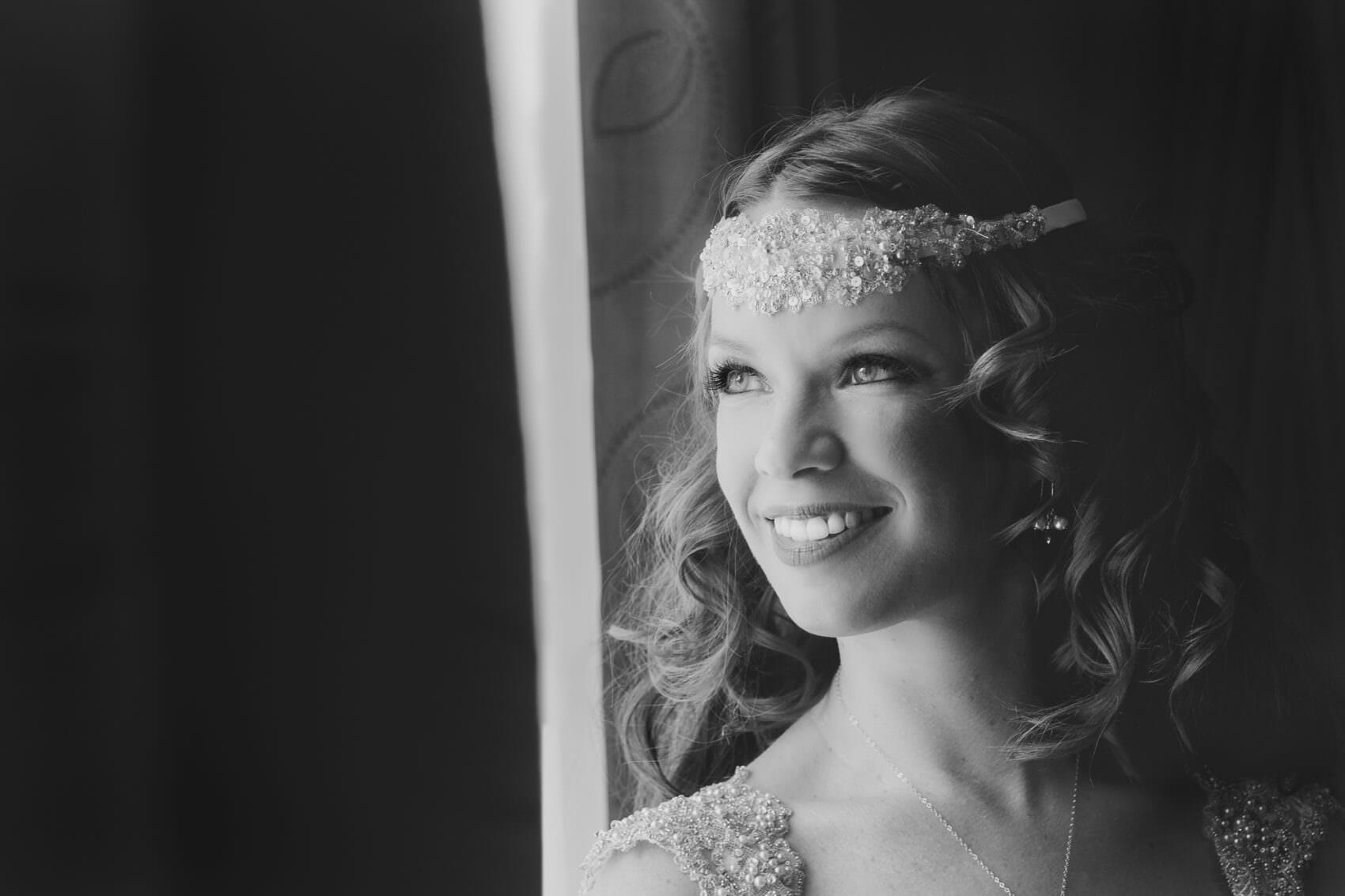 Bride looks out of a window in black & White
