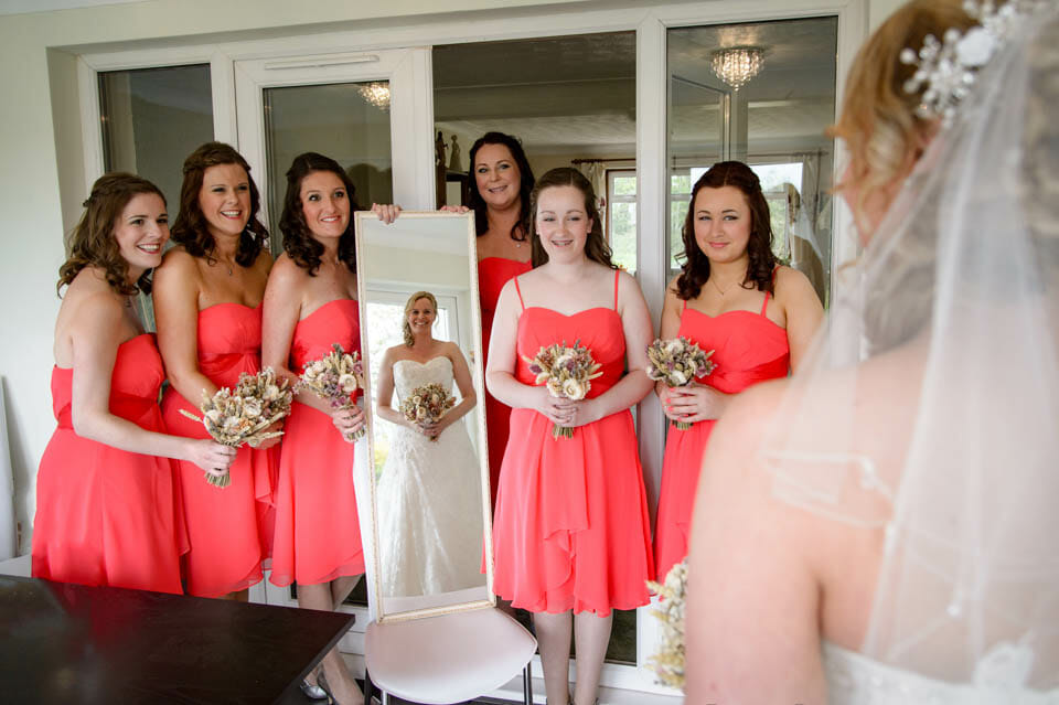 bridemaids hold up a mirror for the bride